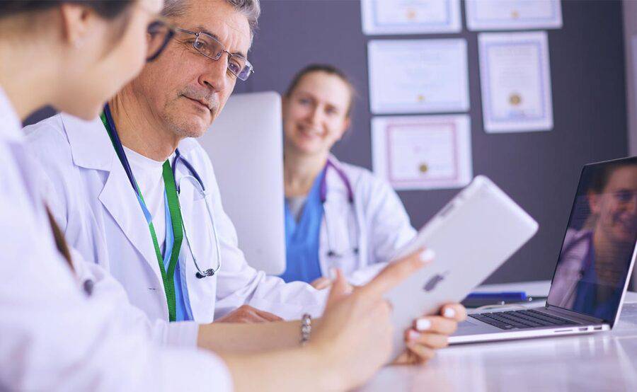 一组医生用平板电脑和笔记本电脑坐在一张表上,代表医学教育和培训程序