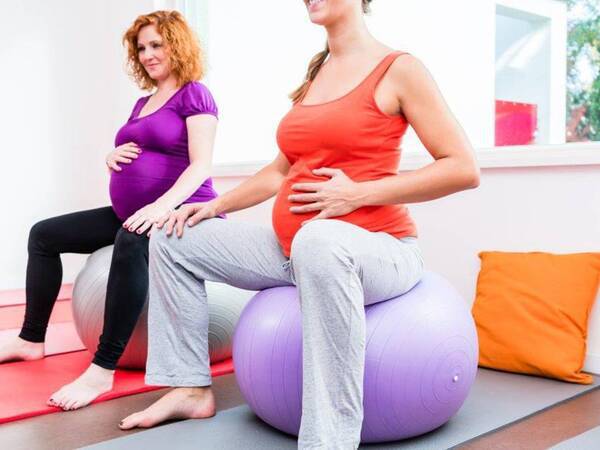两位孕妇在产前课时坐在运动球上